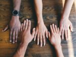 five human hands on brown surface