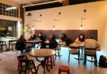 People work on laptops in a cozy coffee shop.