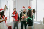 Colleagues celebrating a festive holiday party in an office setting, enjoying drinks and wearing fun costumes.