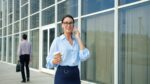 Woman talking on phone holding coffee cup outside office