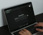 A person typing on a laptop on a table